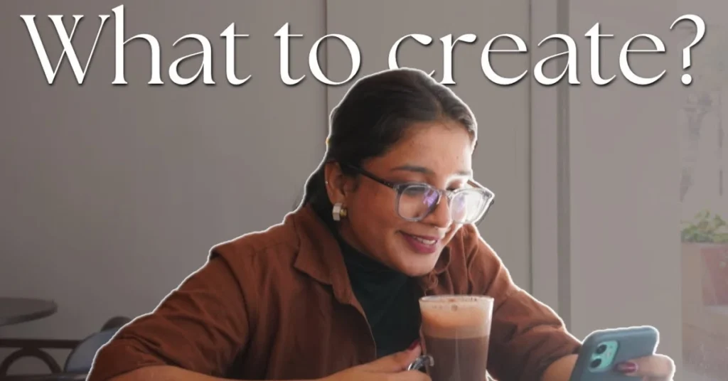 A woman with glasses holds a phone displaying the text "What to create?" with a thoughtful expression.